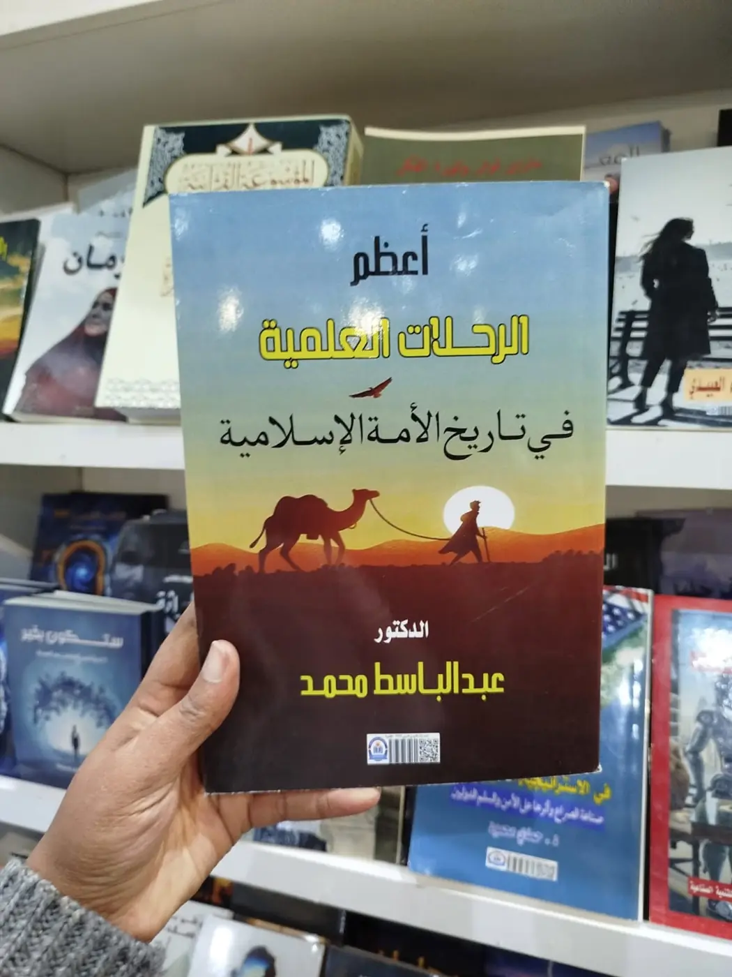 «أعظم الرحلات العلمية في تاريخ الأمة الإسلامية» بين أيدي زوار المعرض، والجزء الأول من الموسوعة القرآنية في الخلفية.