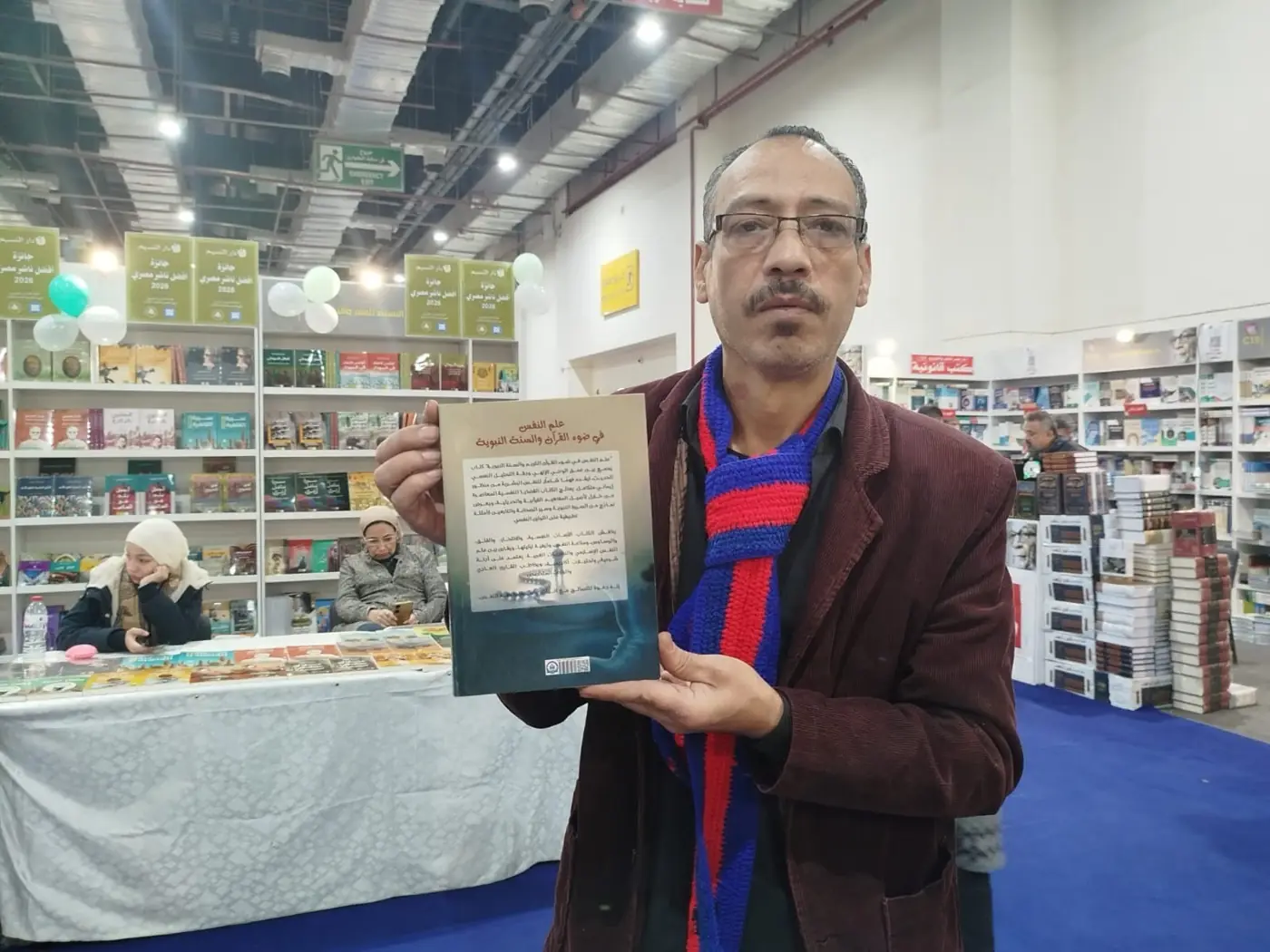 أحد زوار المعرض يحمل كتاب «علم النفس في ضوء القرآن والسنة النبوية» ويعرض غلافه الخلفي.