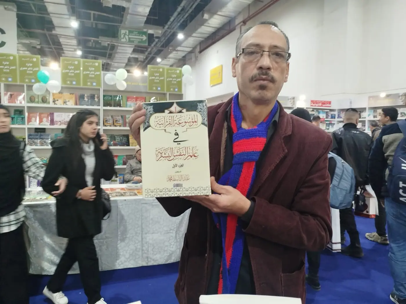 زائر المعرض يحمل الجزء الأول من «الموسوعة القرآنية في علم النفس البشرية».